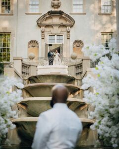 Groom standing in fornt of the Swan House fountain gazing at his Bride who is going begin her walk to the altar with her Dad.