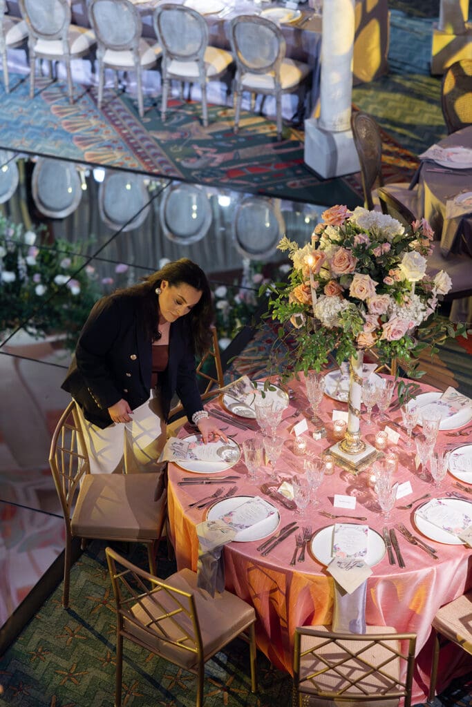 Owner of Tinted Events Planning and Design Jacqueline Vizcaino detailing a guest table with custom elements at the Fox Theatre in Atlanta GA
