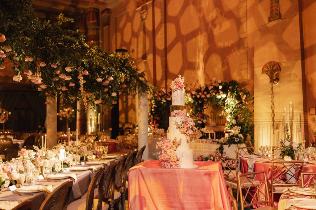 Fox Theatre in Atlanta GA room shot with large brick pattern projection on the 30ft walls, canopy florals over guest estate tables and custom cake on a coral linen.